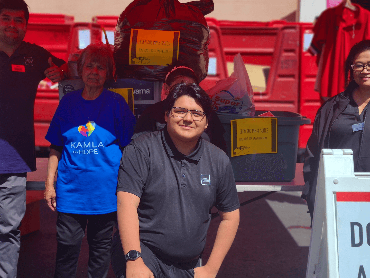 Community donation event: founder with partners, Eden Roc and Salvation Army donation signage in the background